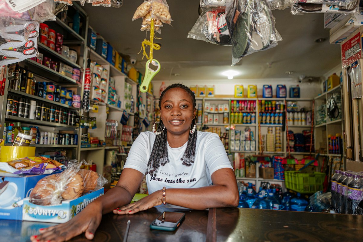 Empreendedora sorrindo atrás do balcão da sua loja
