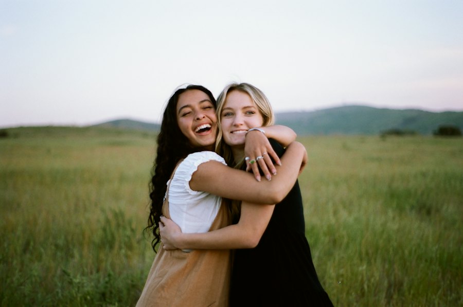 Duas mulheres se abraçando e sorrindo num campo